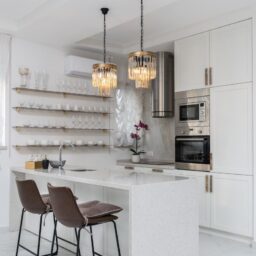 Sleek modern kitchen interior with white cabinets and elegant pendant lights.