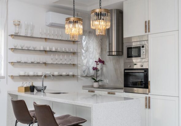Sleek modern kitchen interior with white cabinets and elegant pendant lights.