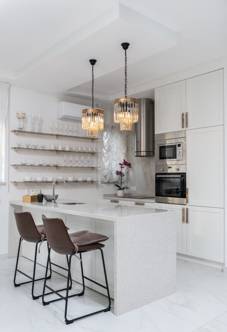 Sleek modern kitchen interior with white cabinets and elegant pendant lights.